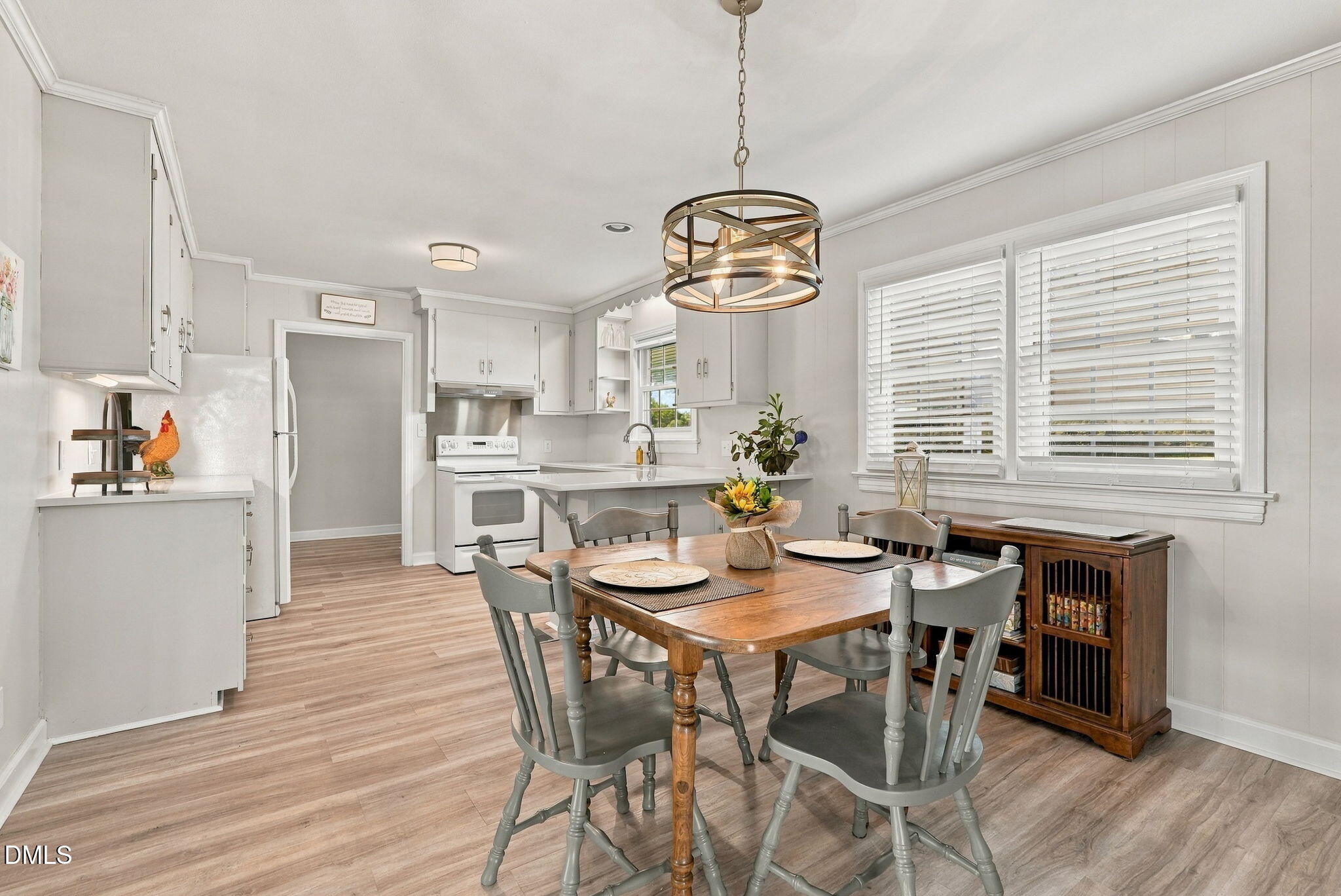 Kitchen and dining area with white cabinets, a wood table, gray chairs, and large windows.