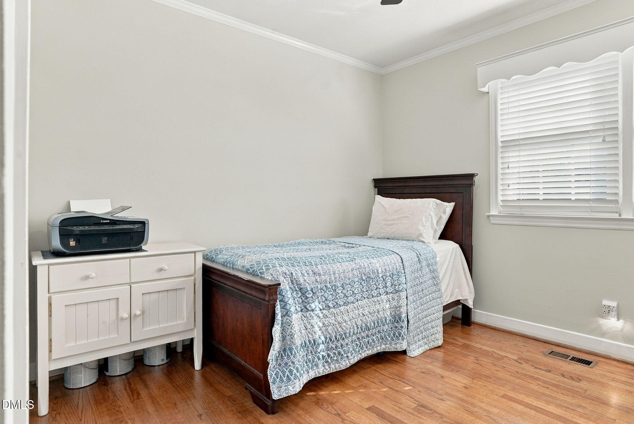 Bedroom with a dark wood single bed, patterned blue quilt, and hardwood floors.