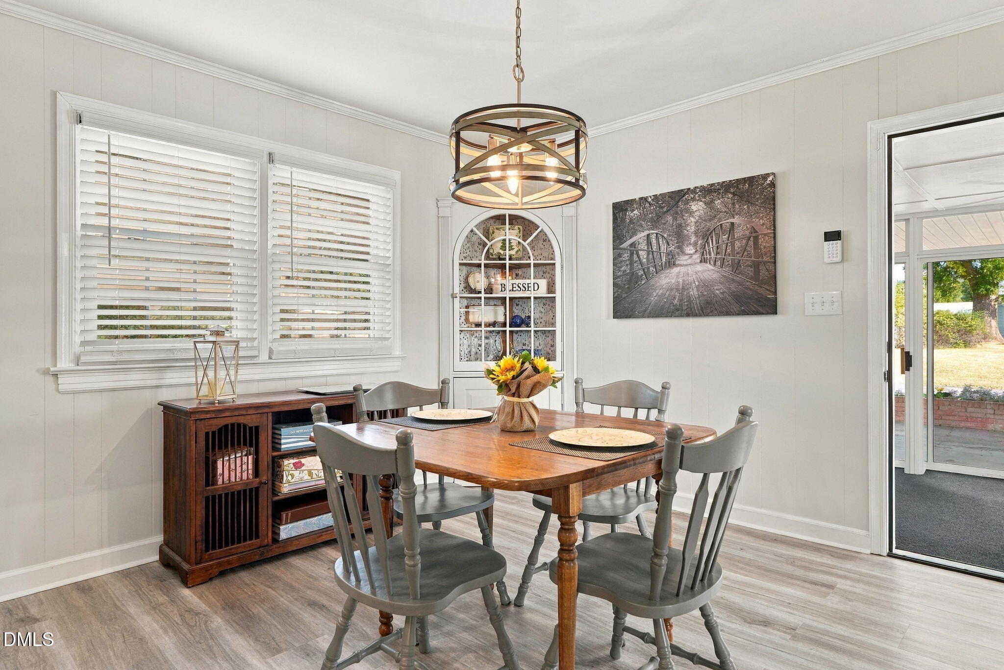 Dining room with a wooden table, gray chairs, circular chandelier, and built-in display cabinet.