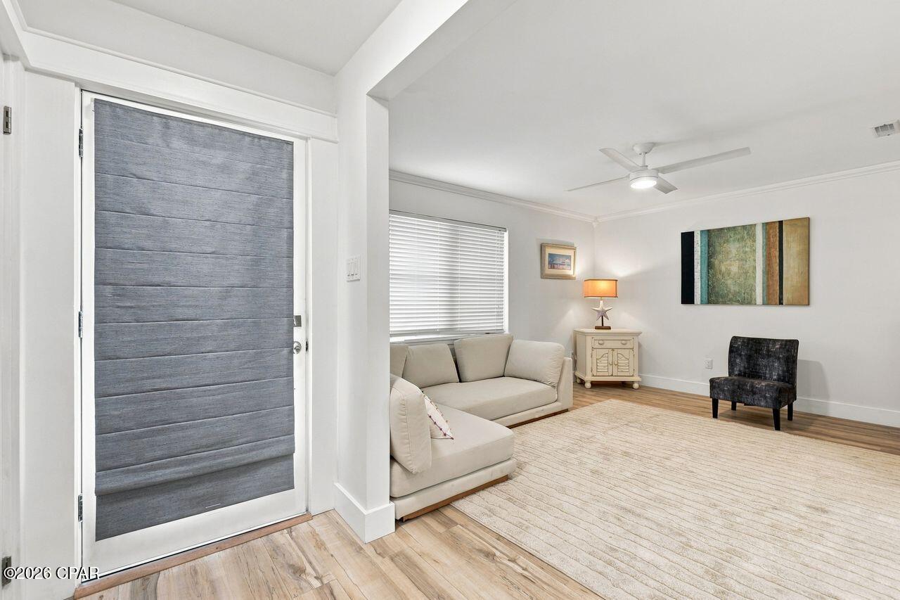 Living room with a gray paneled entry door, cream sectional sofa, and light area rug.
