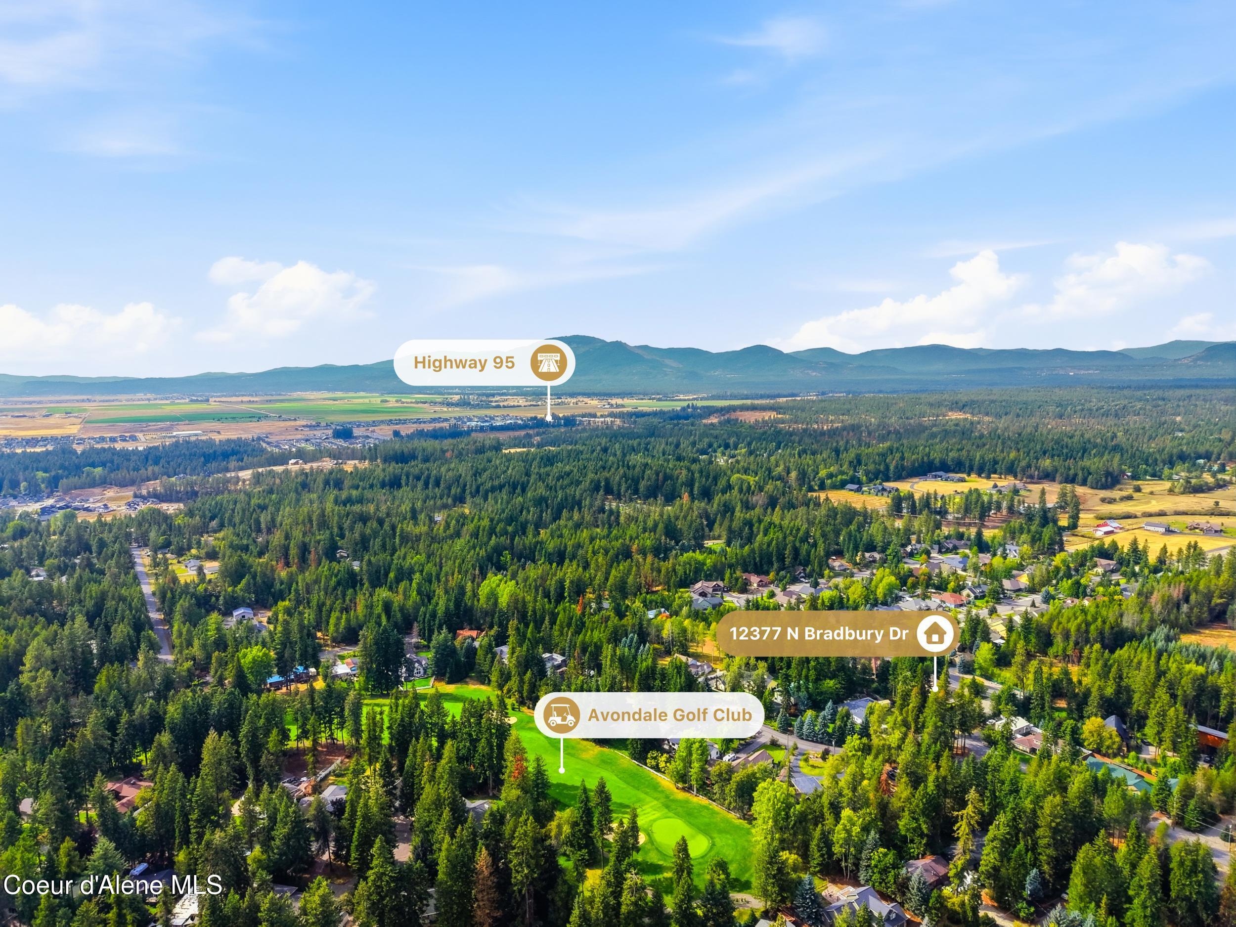 Aerial view of 12377 N Bradbury Dr among forested homes, beside Avondale Golf Club with mountains beyond.