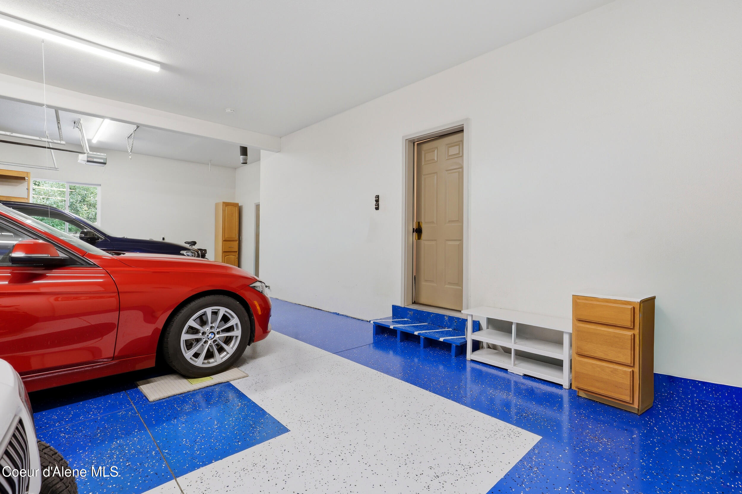Garage with blue-and-white speckled flooring, a red car, and a tan interior door.
