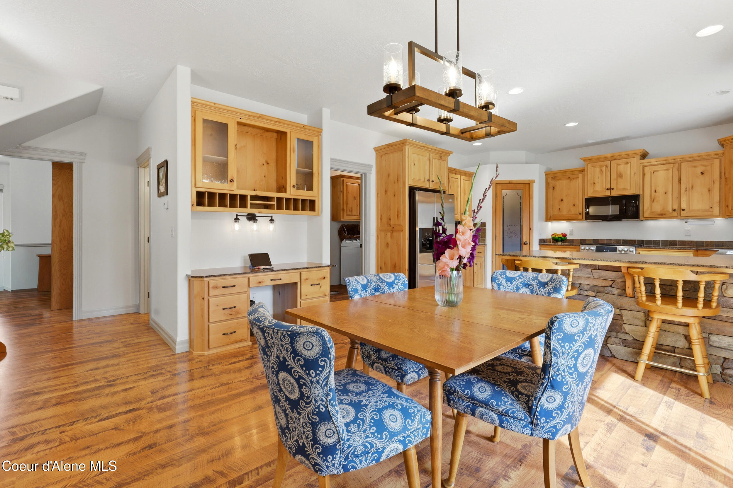Kitchen and dining area with honey-toned wood cabinets, stone-front breakfast bar, and blue patterned chairs.