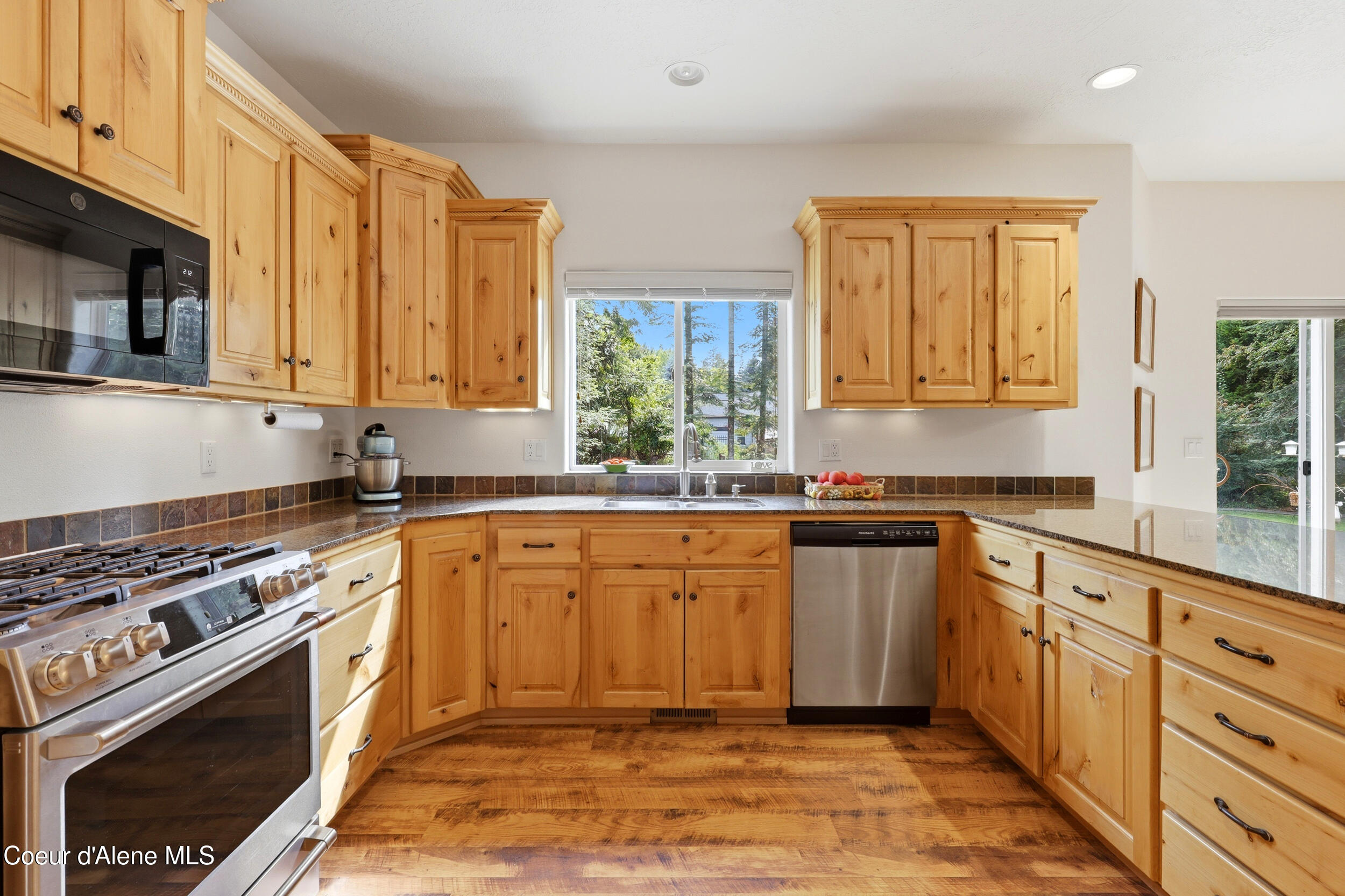 Kitchen with honey-colored wood cabinets, granite counters, and stainless steel appliances.