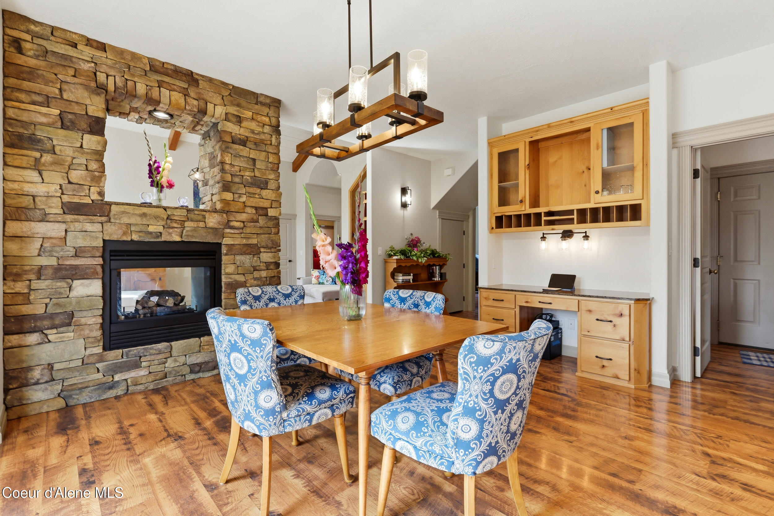 Dining room with blue patterned chairs, a stone fireplace, and built-in wood cabinetry.