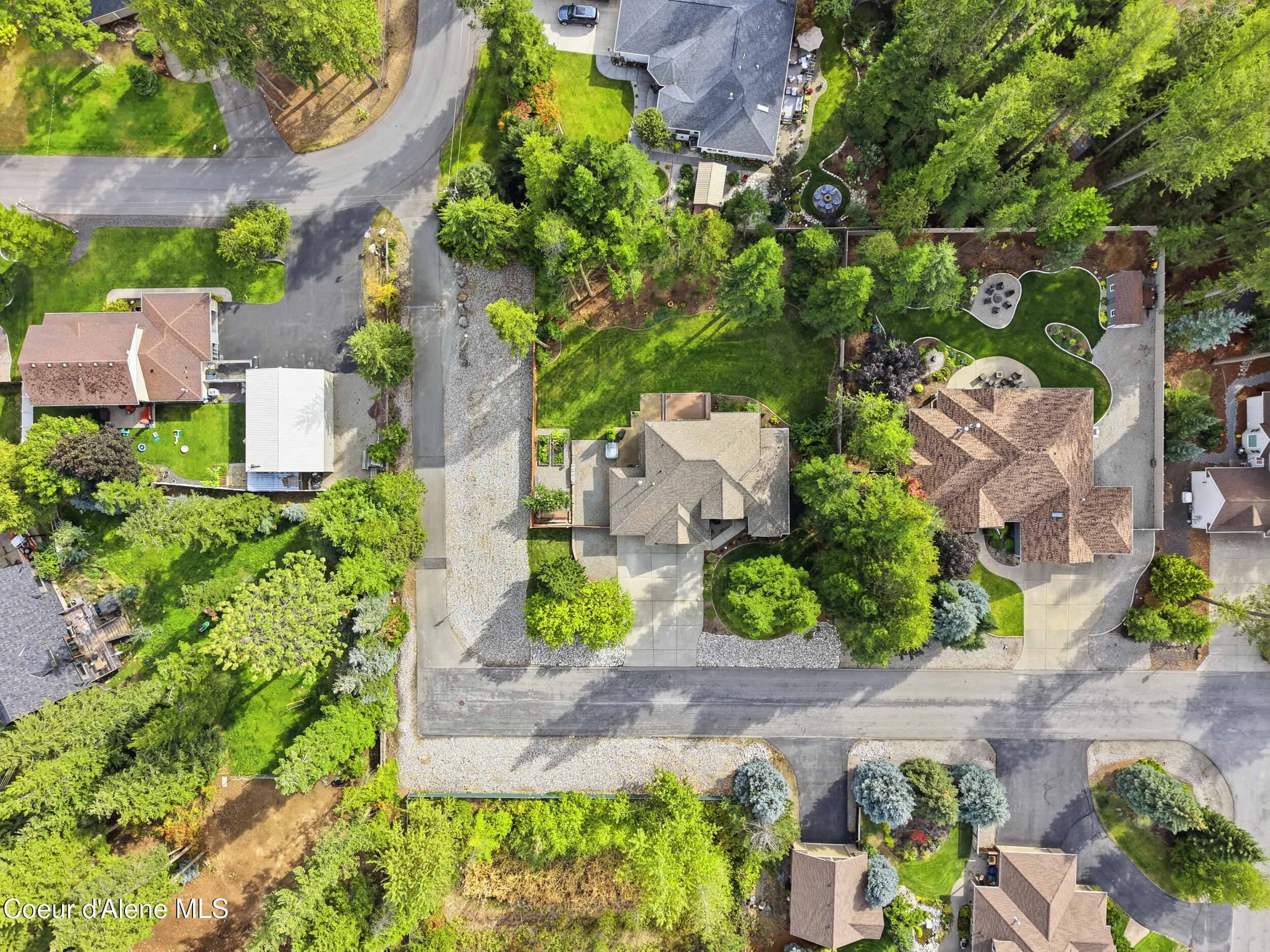Aerial view of a home with a broad gravel driveway and landscaped grounds.