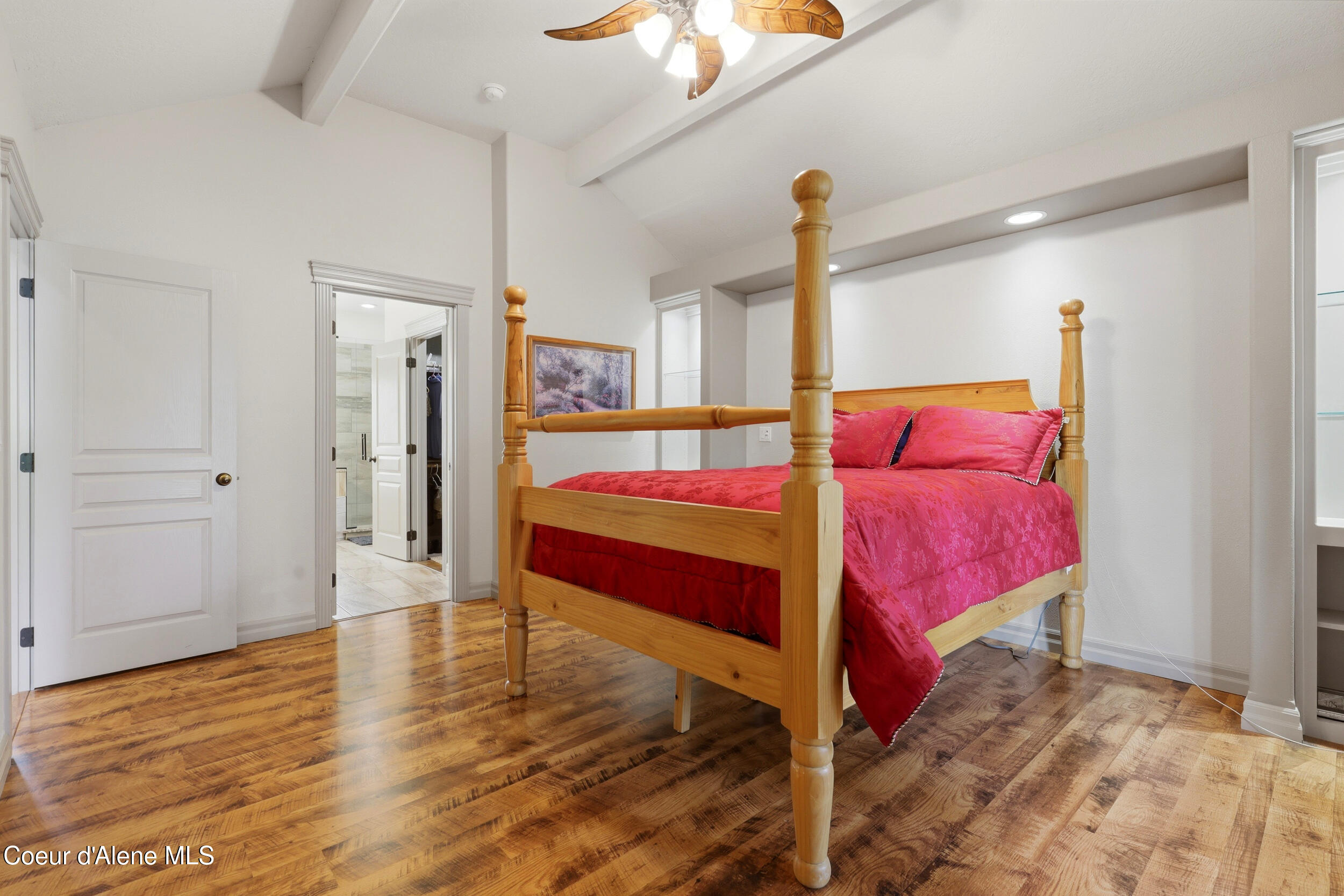 Bedroom with a wooden four-poster bed dressed in bright pink bedding and polished wood floors.