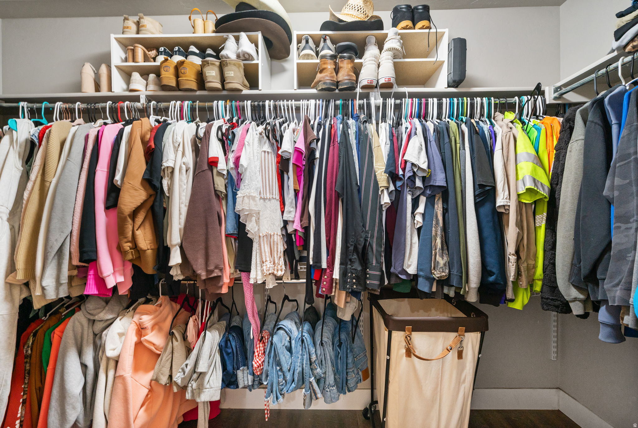 Walk-in closet with extensive clothing racks, shoe shelves, and a laundry hamper.