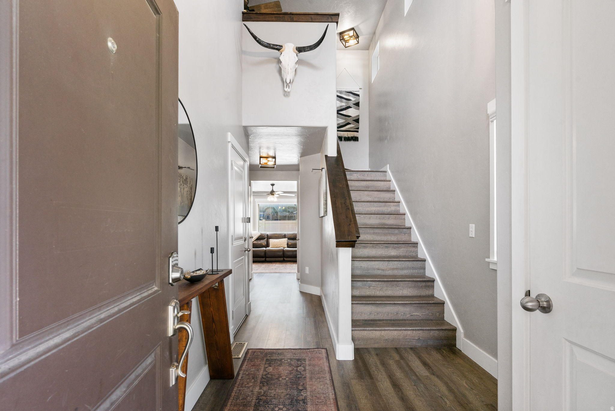 Entry hall with carpeted stairs, dark wood railing, and a longhorn skull mounted above.