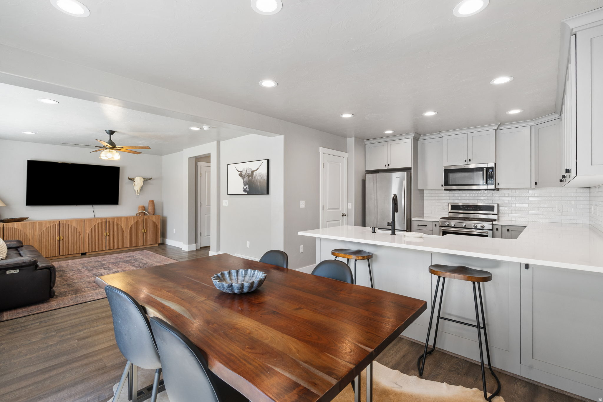Open-plan kitchen and dining area with gray cabinets, a white island, and a large wood dining table.