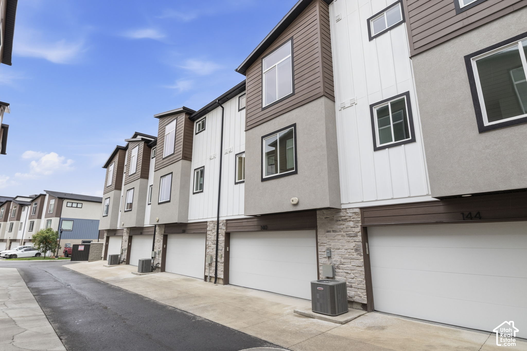 Attached townhomes with individual garage doors, stone accents, and a shared driveway.