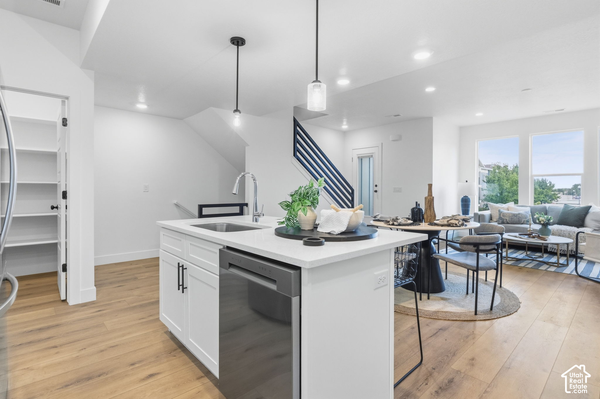 Open-plan kitchen with a white island, leading to a dining area and bright living room.