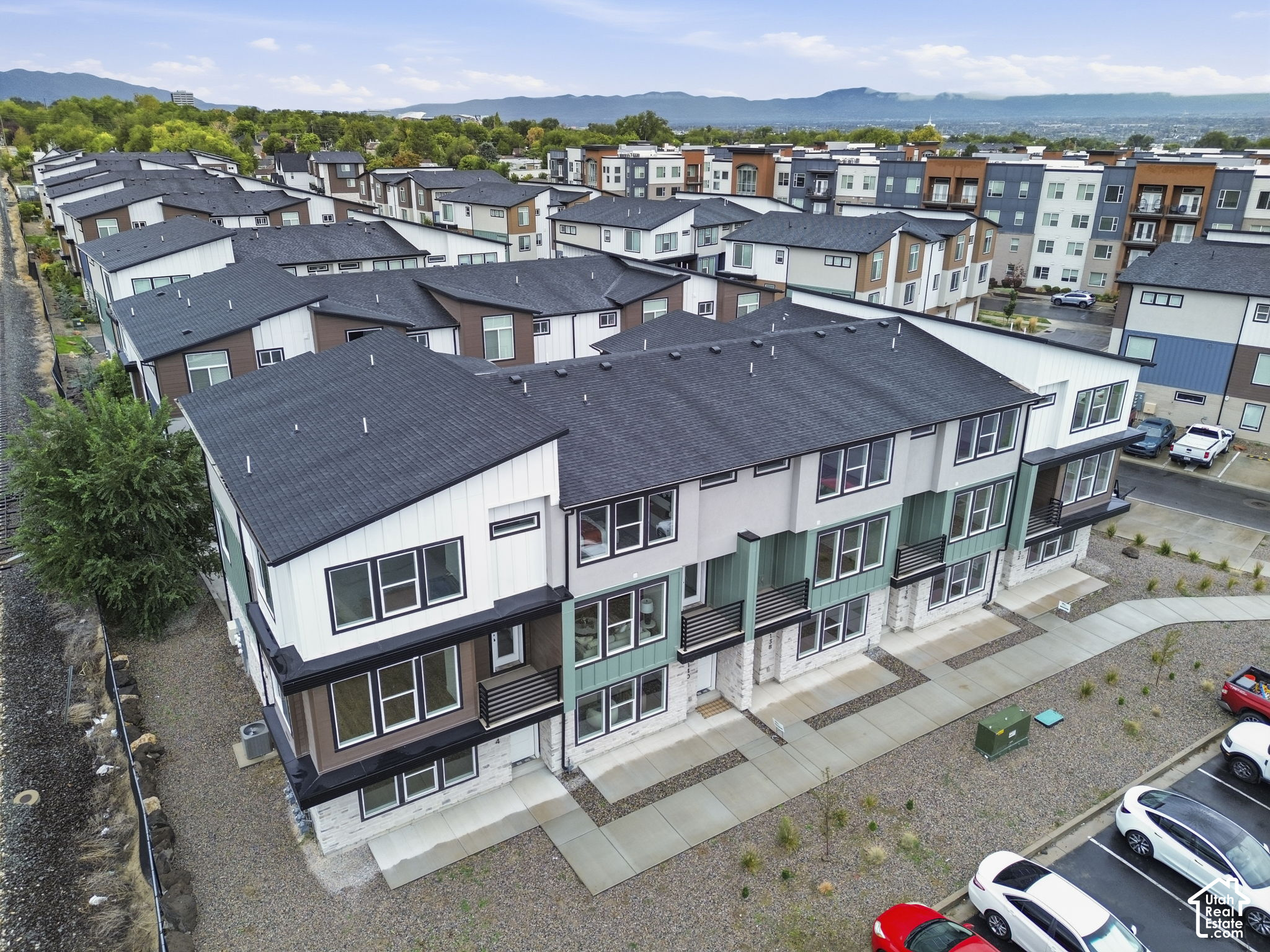 Aerial view of modern attached townhomes with varied facades and mountains in the distance.