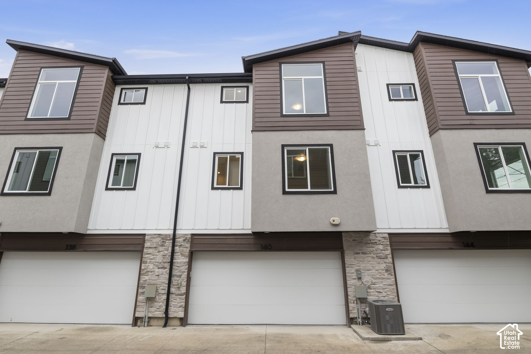 Townhouse exterior with brown and white siding, stone accents, and an attached garage.