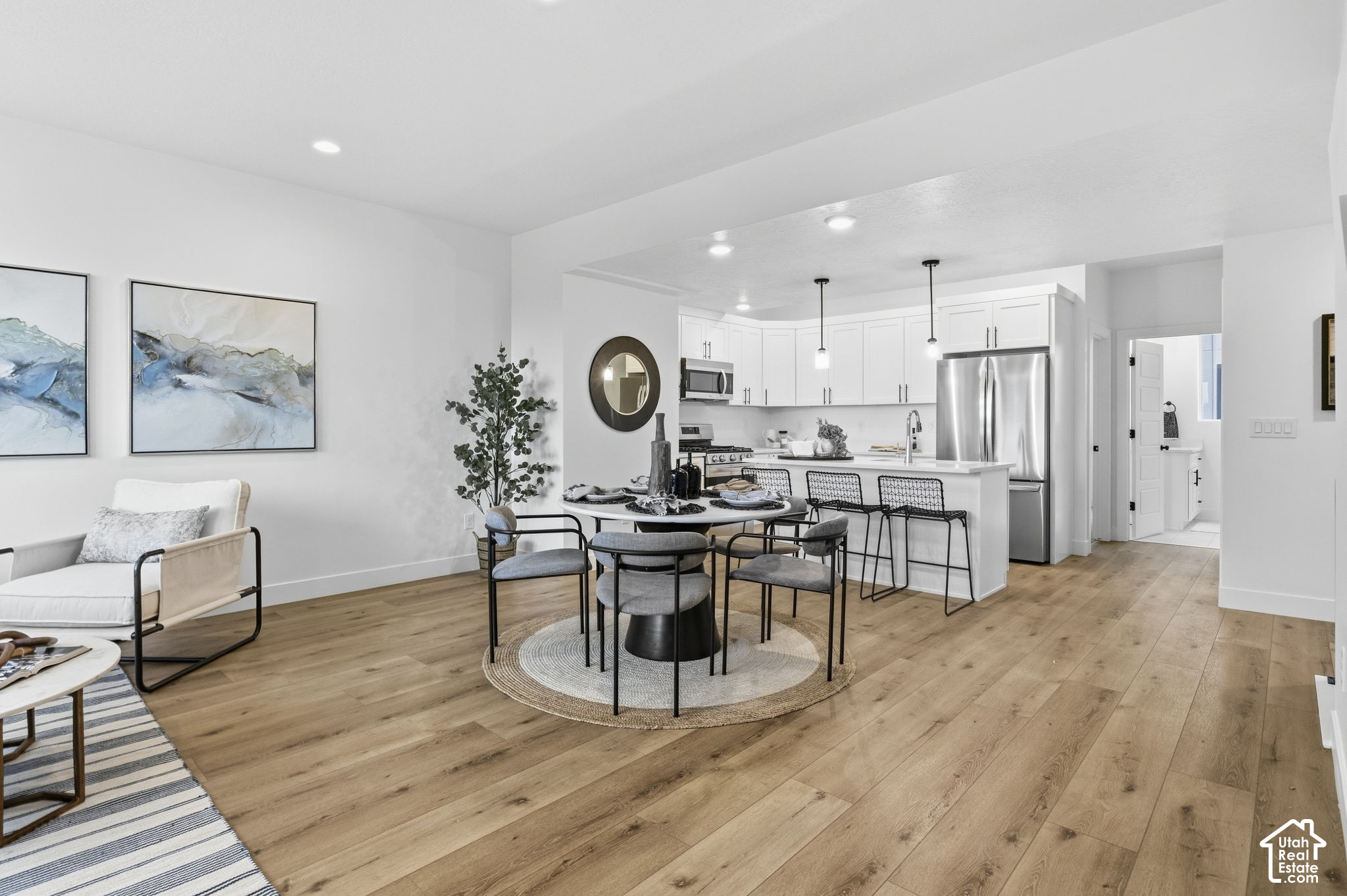 Open-plan kitchen and dining area with white cabinetry, stainless appliances, and a round table.