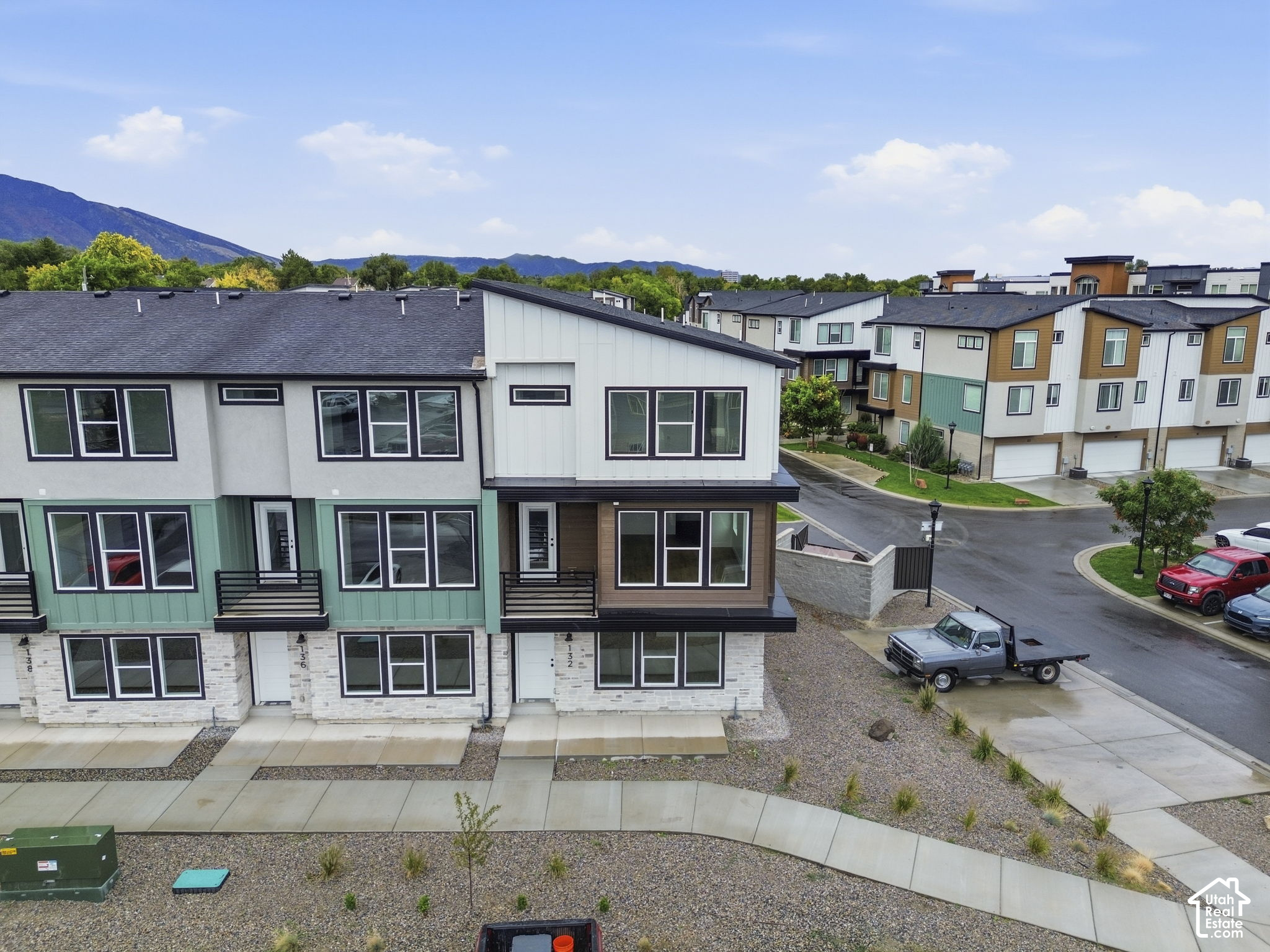 Modern townhomes with teal and brown facade accents, gravel landscaping, and mountains in the distance.