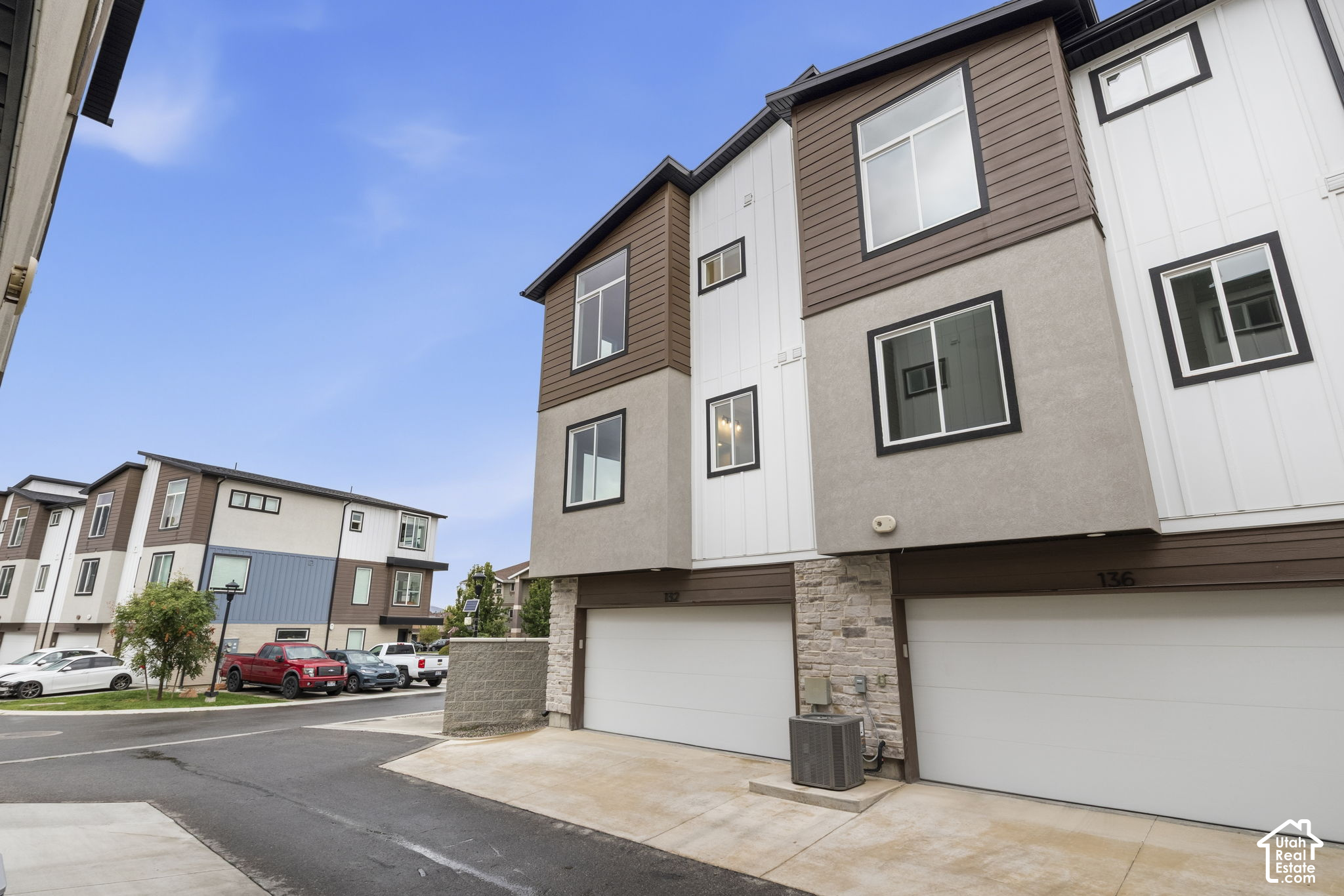 Modern attached home with brown and white siding, stone accents, and a garage in a townhouse row.