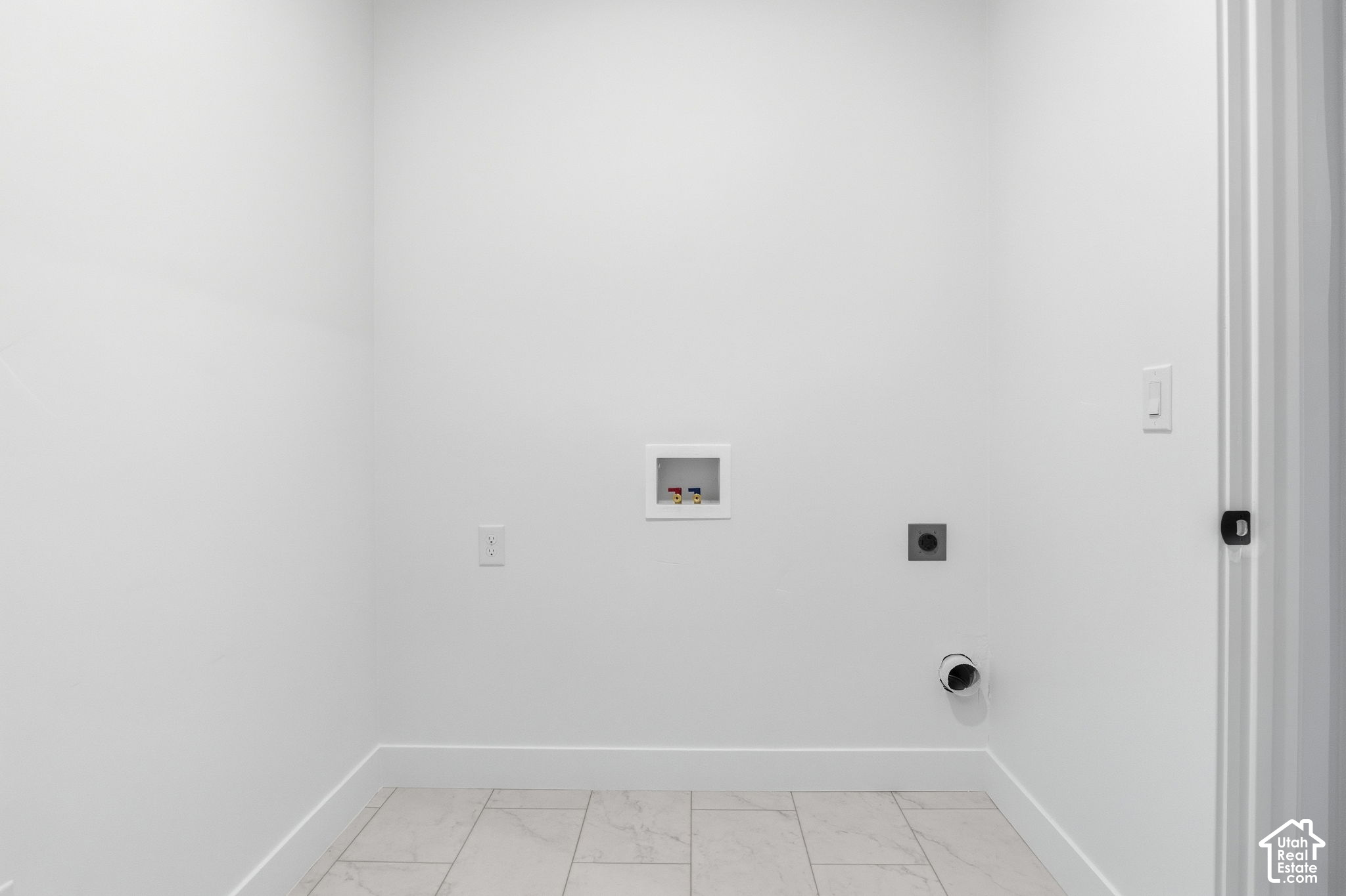 Empty laundry room with washer hookups and light tile flooring.