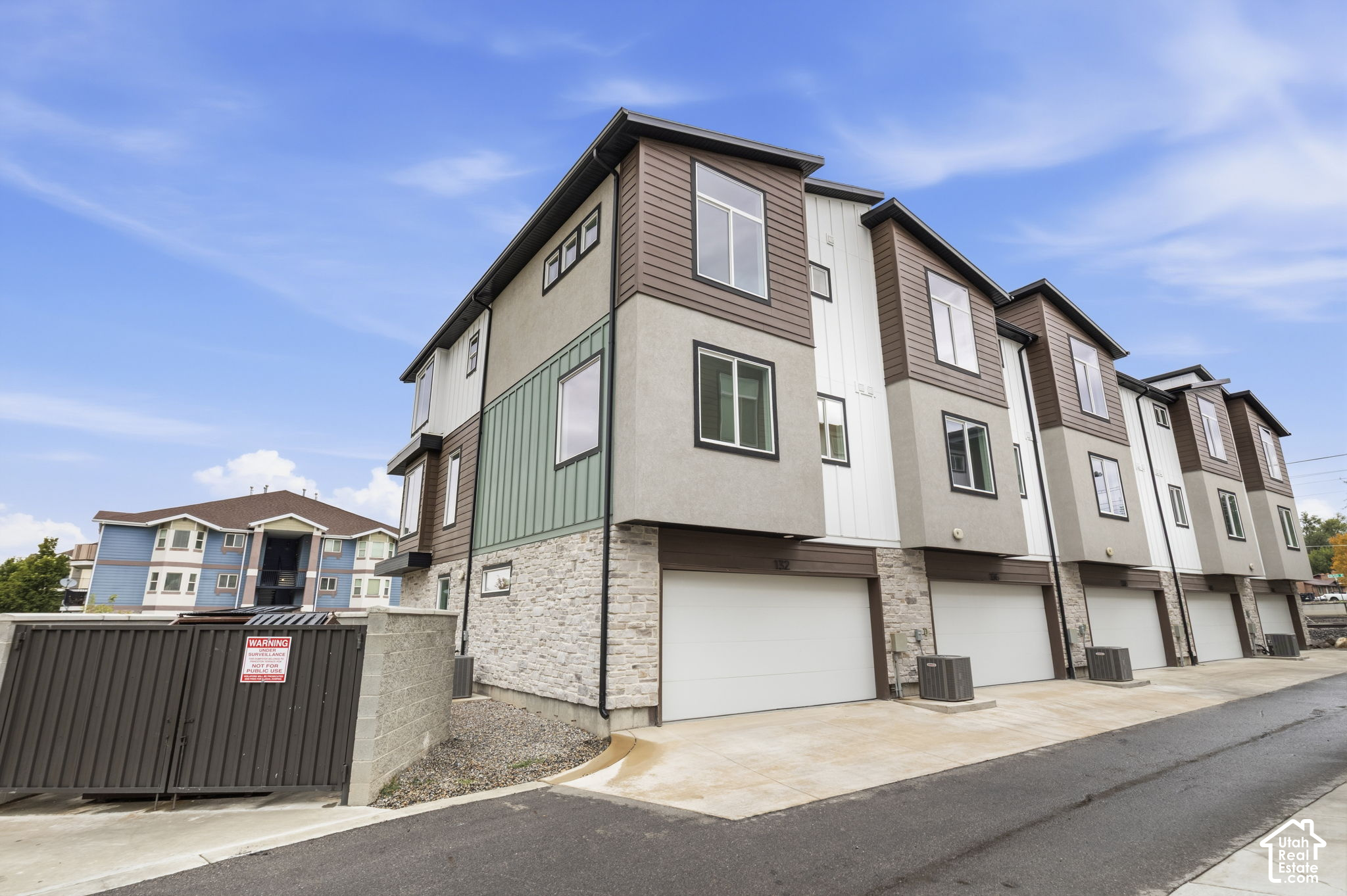 Modern multi-story townhomes with attached garages and mixed stone and panel siding.