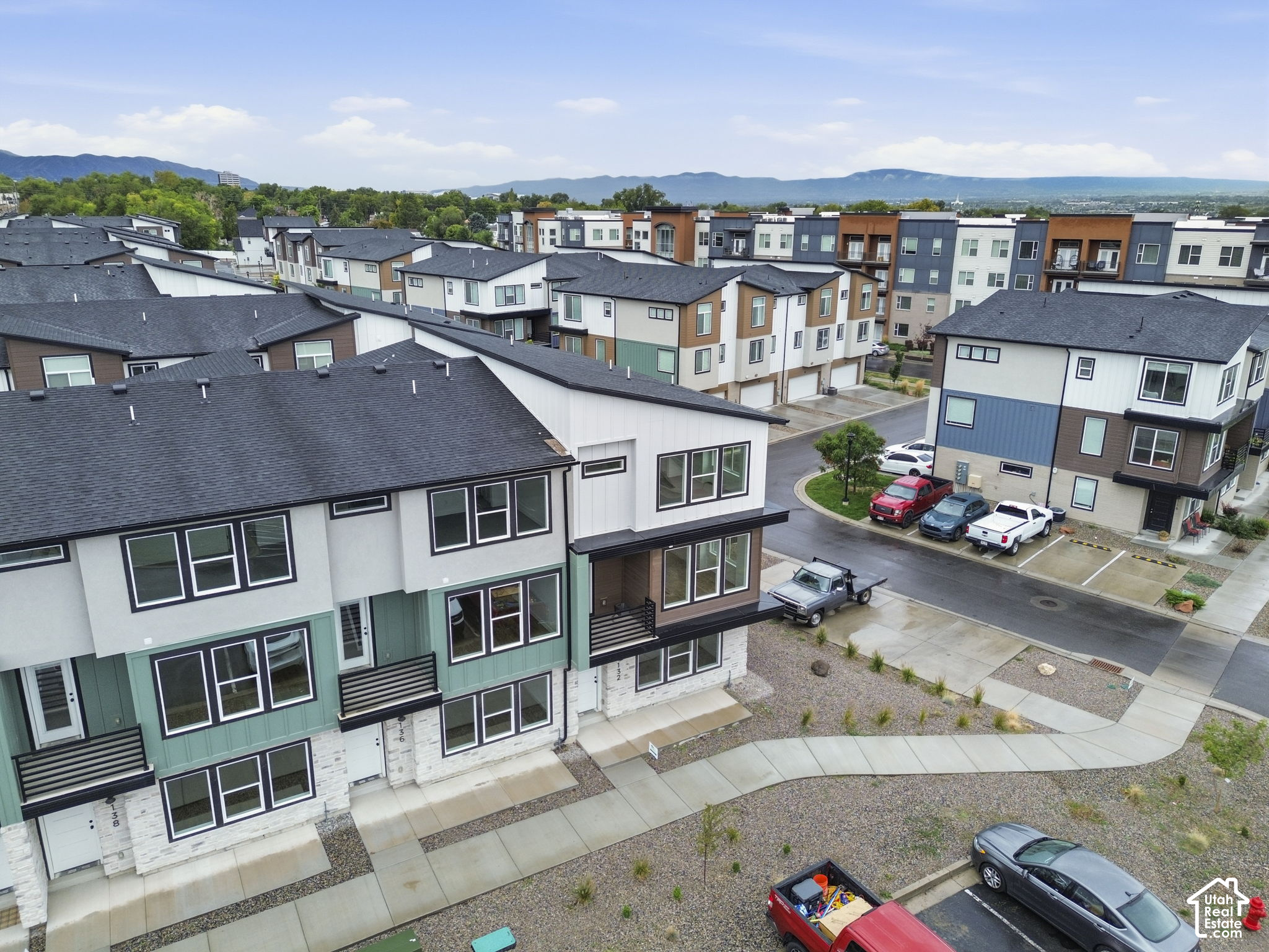 Aerial view of modern townhomes with shared streets and mountains in the distance.