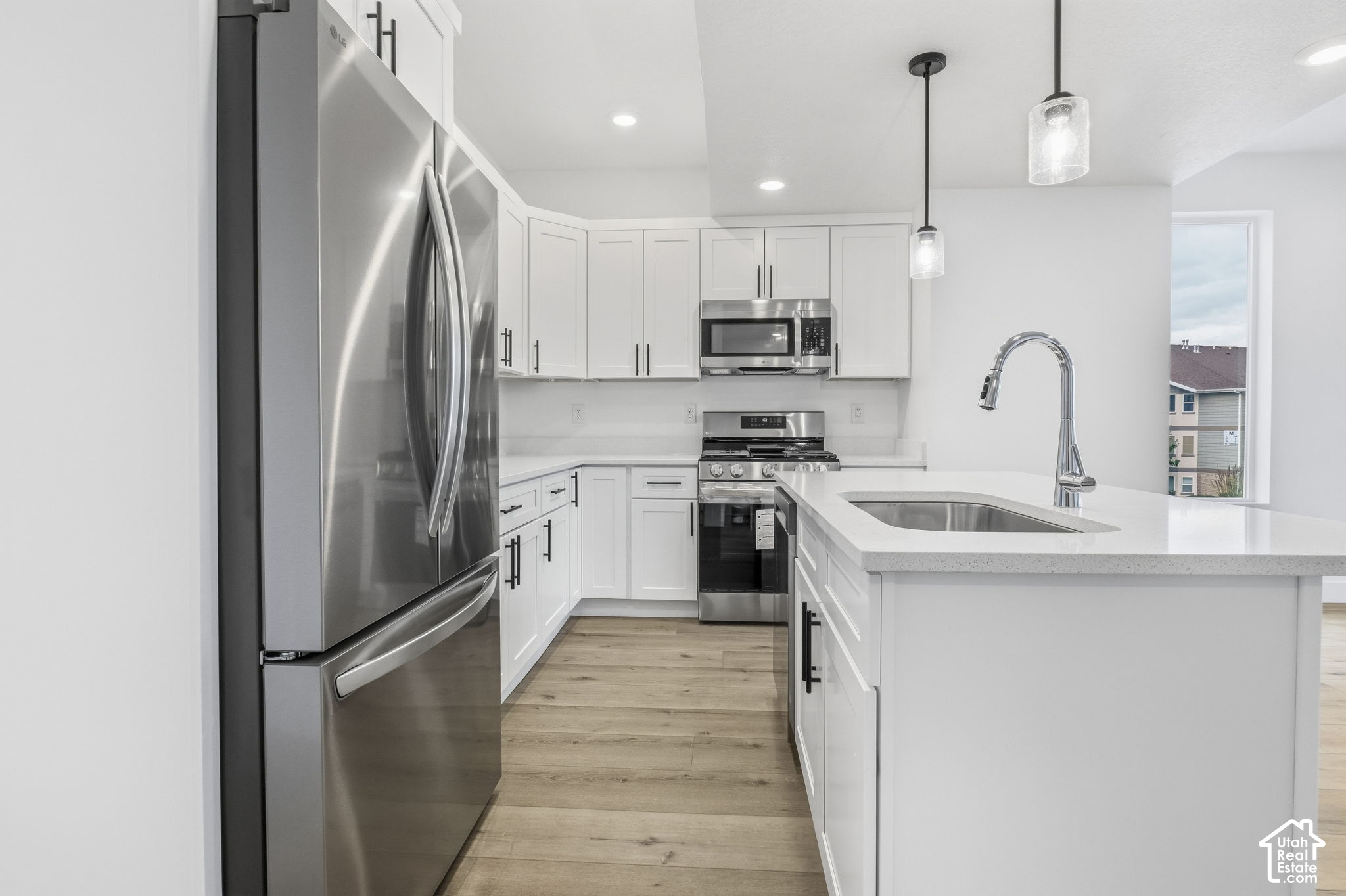Modern white kitchen with stainless steel appliances and a large island sink.
