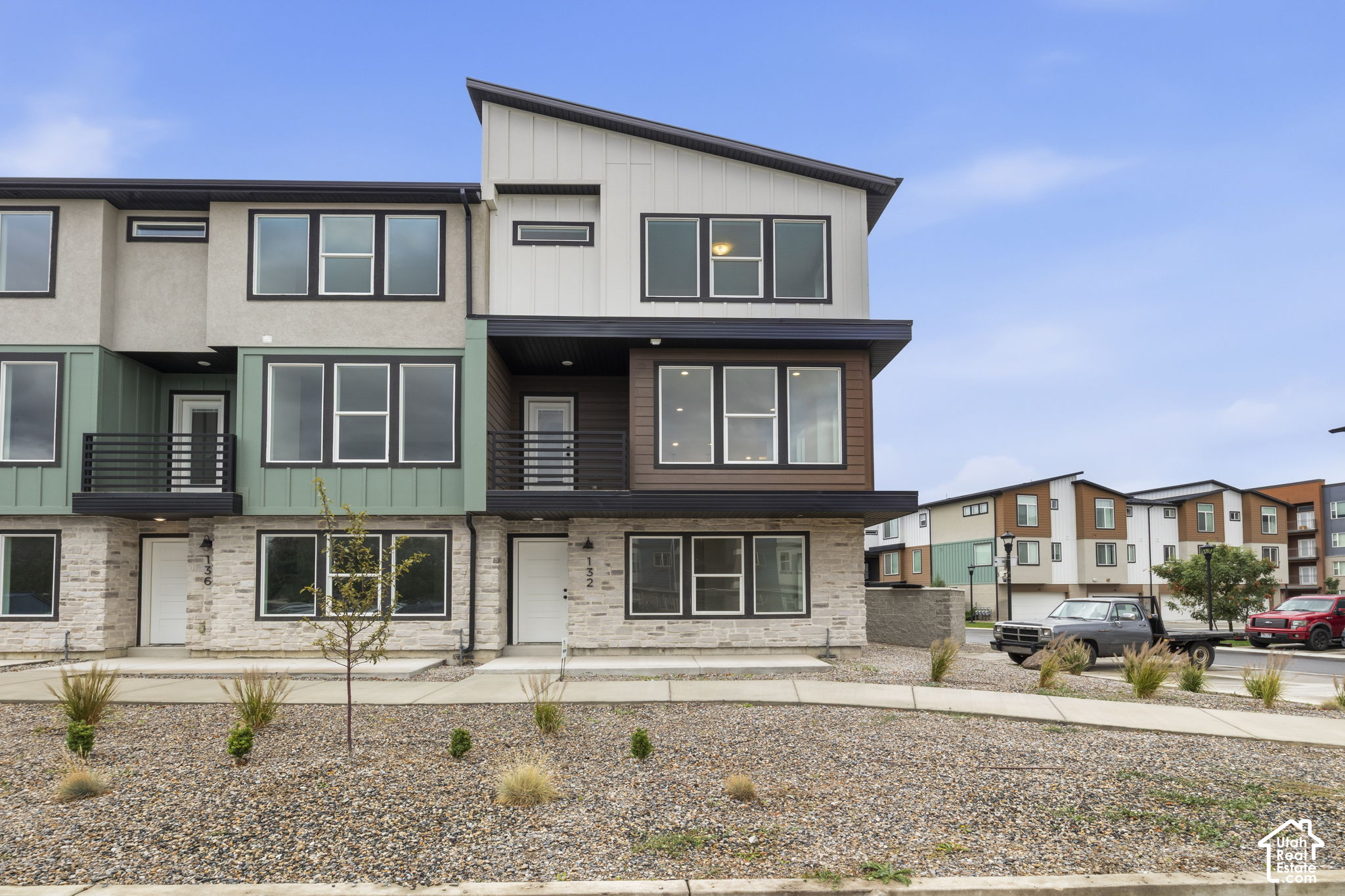 Modern townhouse with multicolored siding, stone facade, and gravel front landscaping.