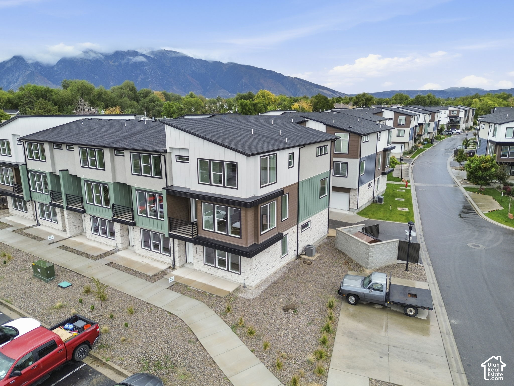 Aerial view of modern townhomes with varied siding and mountains in the distance.