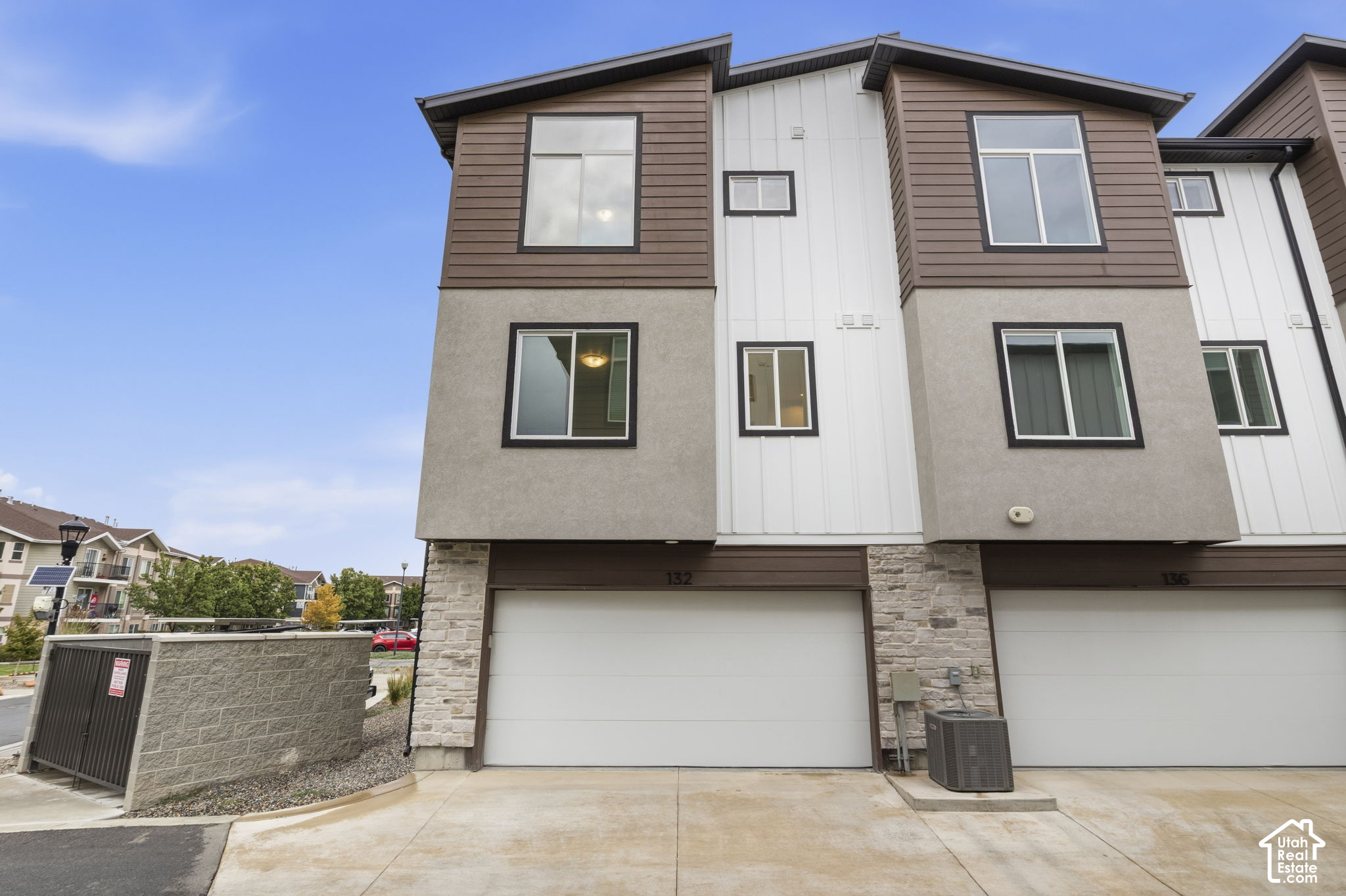 Attached multi-story home with brown and white siding, stone accents, and a front-facing garage.