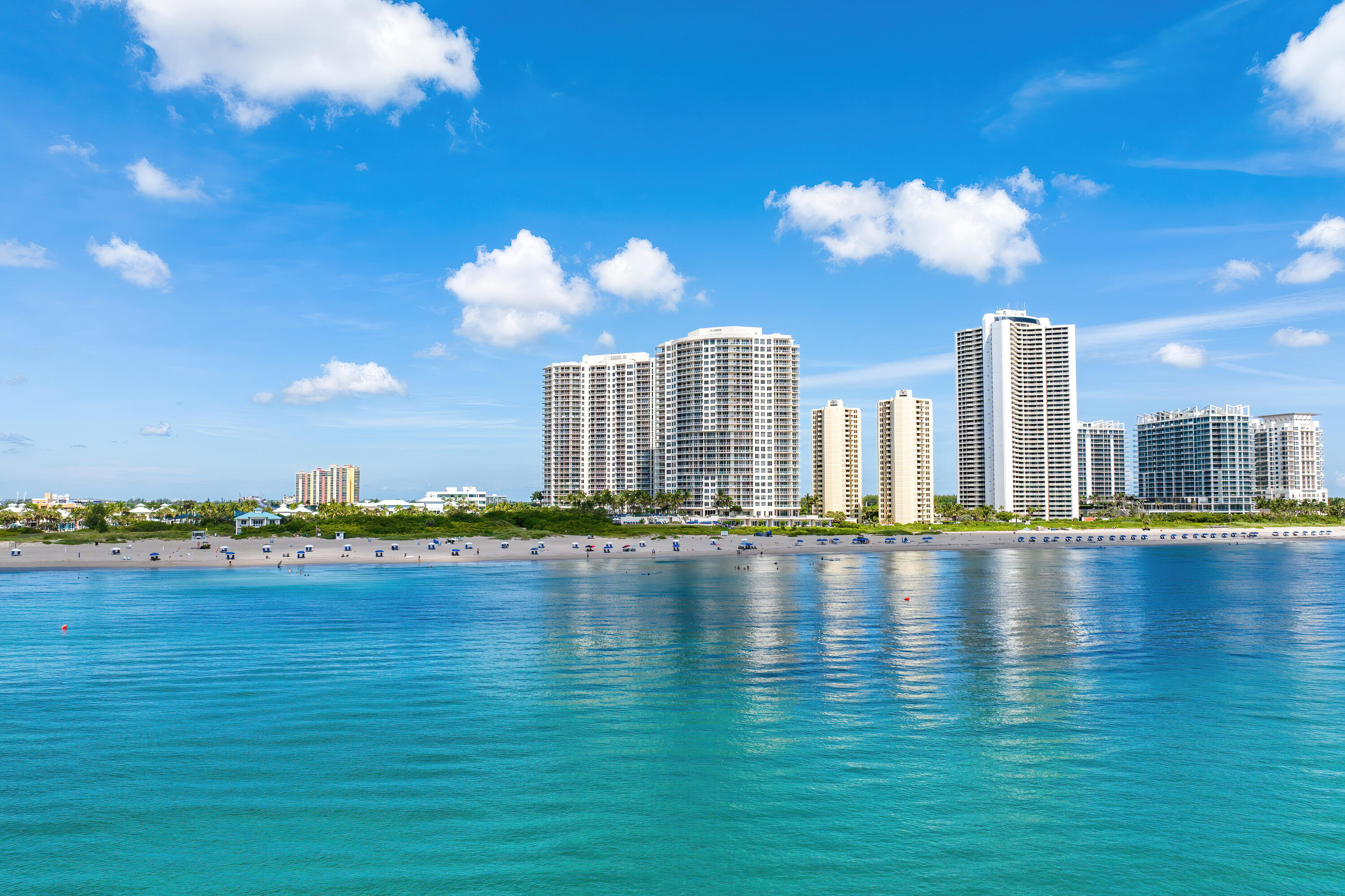 Beachfront high-rise condominiums line the shore across calm turquoise water.