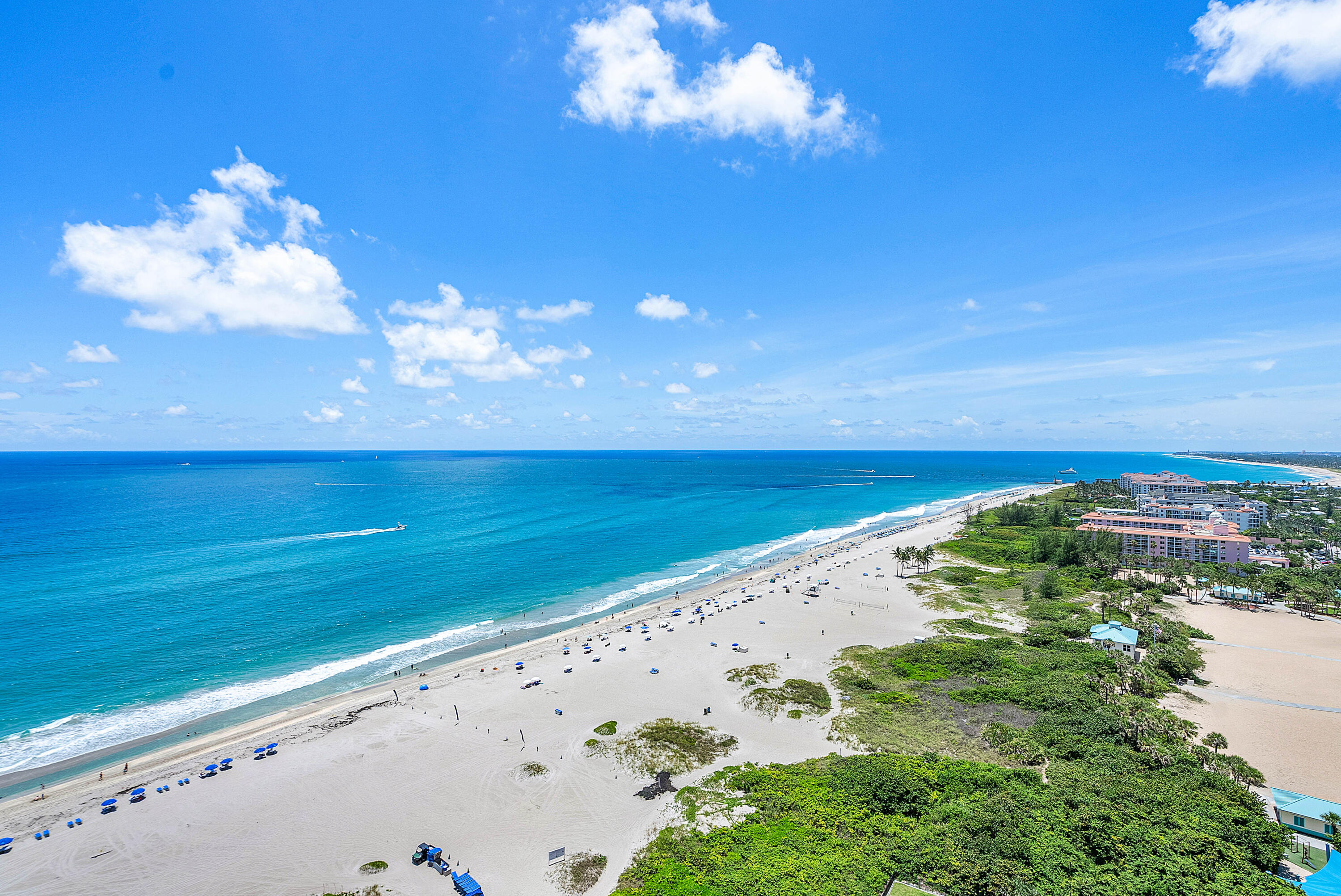Aerial ocean and beach view with turquoise water, sandy shoreline, and coastal resorts.