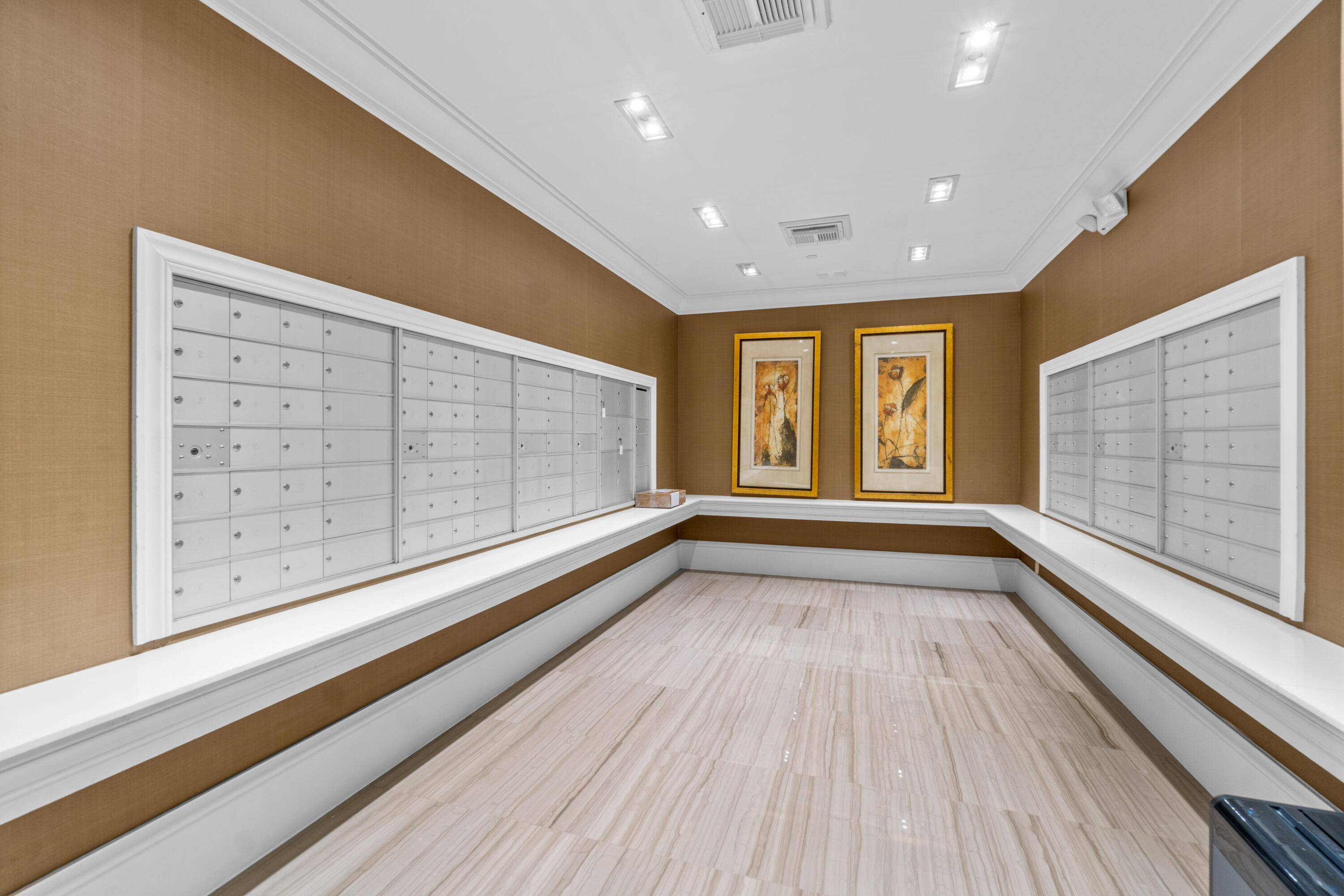 Condominium mailroom with rows of white mailboxes and framed artwork on the far wall.