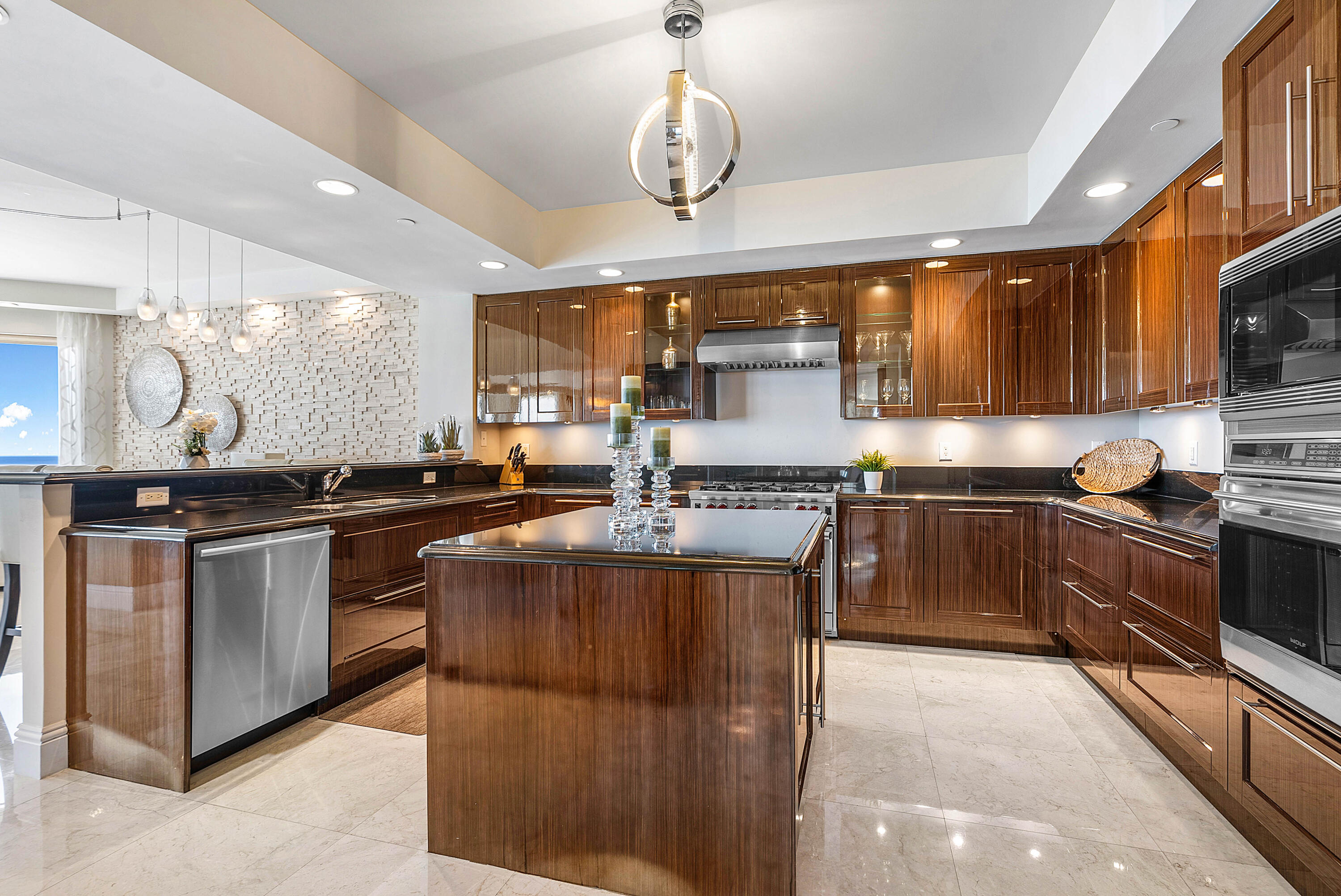 Modern kitchen with dark wood cabinets, a central island, stainless steel appliances, and a partial ocean view.