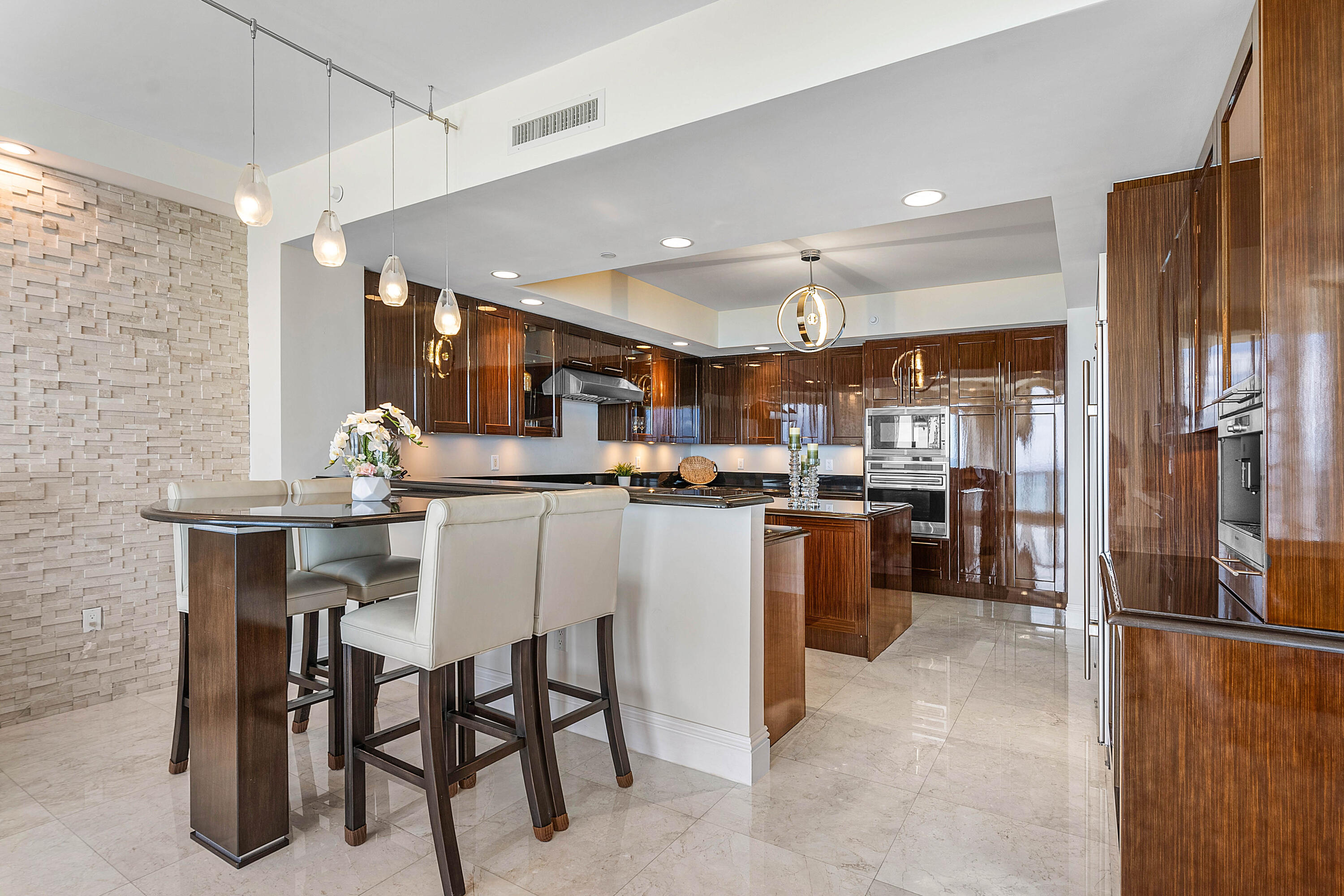 Modern kitchen with dark wood cabinets, white island, stainless appliances, and a raised counter with stools.