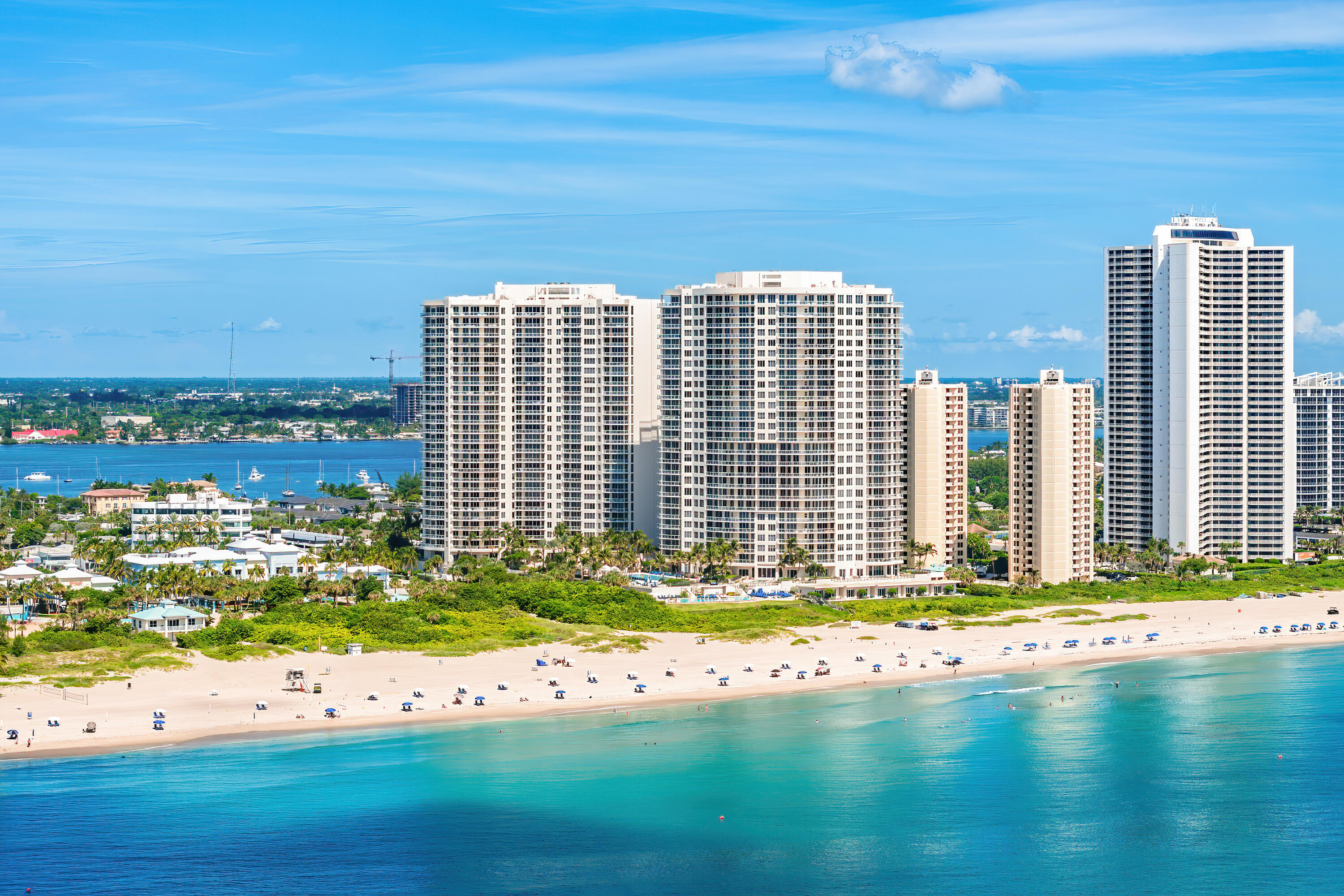 Beachfront high-rise condominiums overlooking a broad sandy beach and turquoise ocean.
