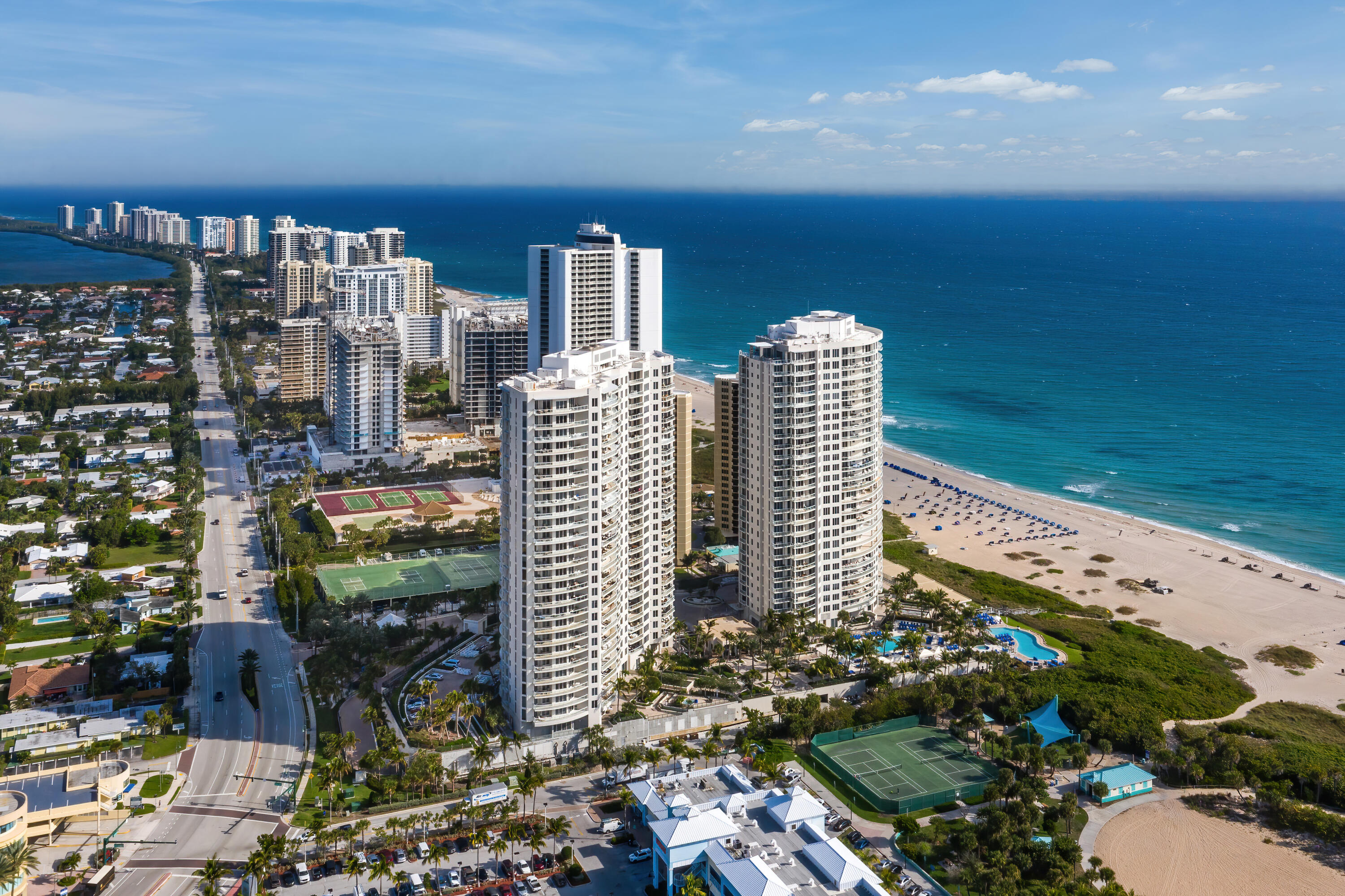 Oceanfront condominium towers beside the Atlantic beach, with pools and tennis courts visible below.