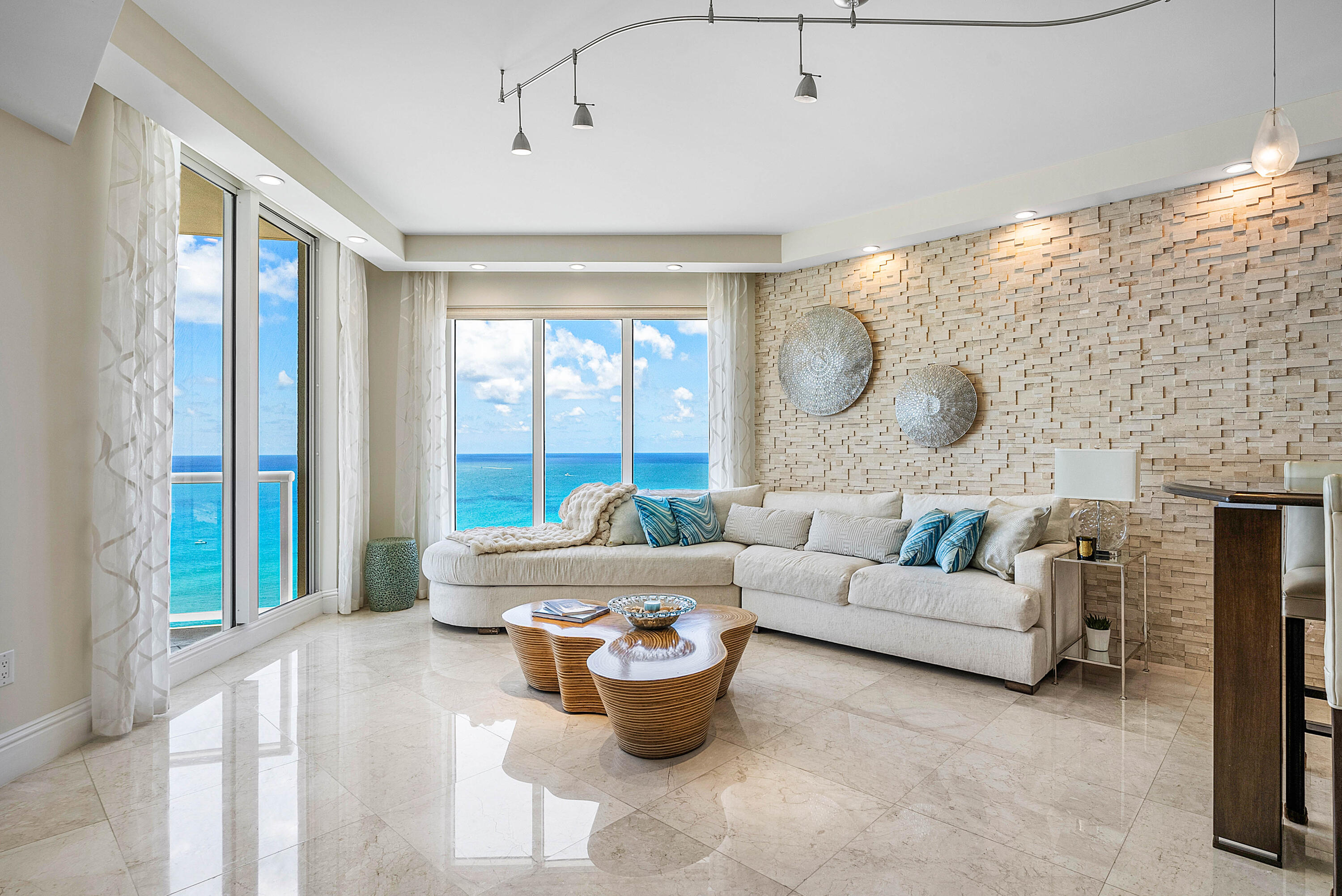 Living room with a white sectional and ocean views through floor-to-ceiling windows.