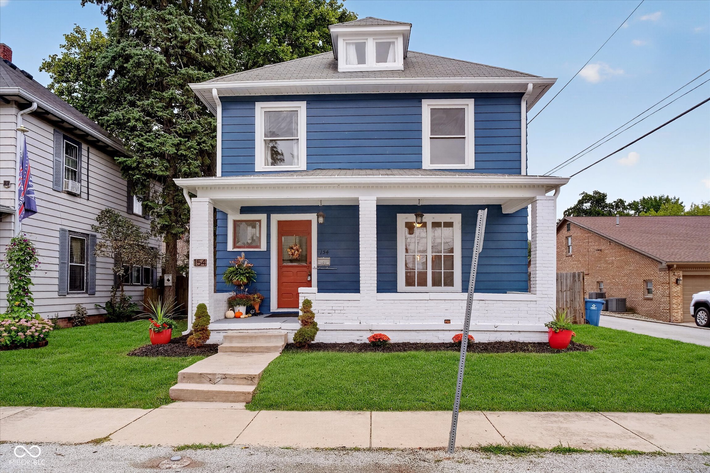 Blue two-story house with white trim, a red front door, and a covered porch.