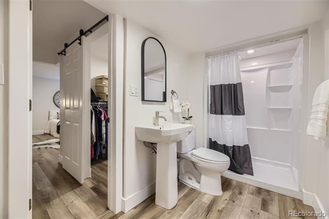 Bathroom with a pedestal sink and tub-shower, opening to a closet and adjoining bedroom.