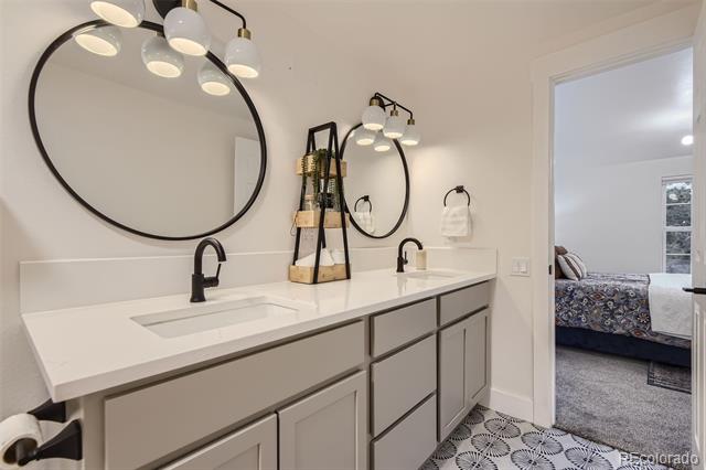 Bathroom with a double vanity, oversized oval mirrors, and patterned floor tile.
