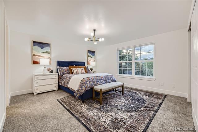 Bedroom with a navy bed, patterned bedding, a large rug, and a wide window overlooking trees.