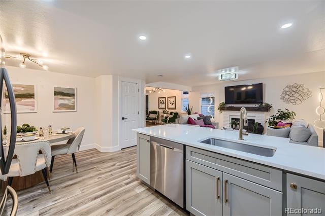 Open-plan kitchen with a large white island, gray cabinets, and adjoining dining and living areas.