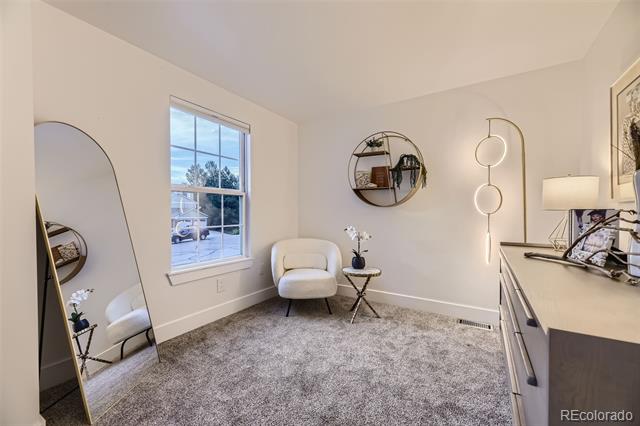 Bright home office with gray carpet, a white chair, circular wall shelves, and a tall arched mirror.