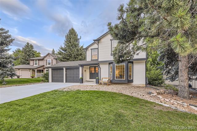 Two-story home with a double garage, broad driveway, and mature pine trees.