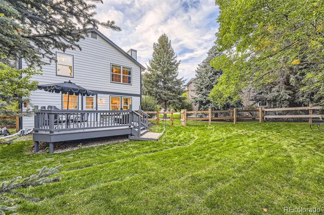 Gray-sided home with a raised deck overlooking a grassy, tree-lined backyard.