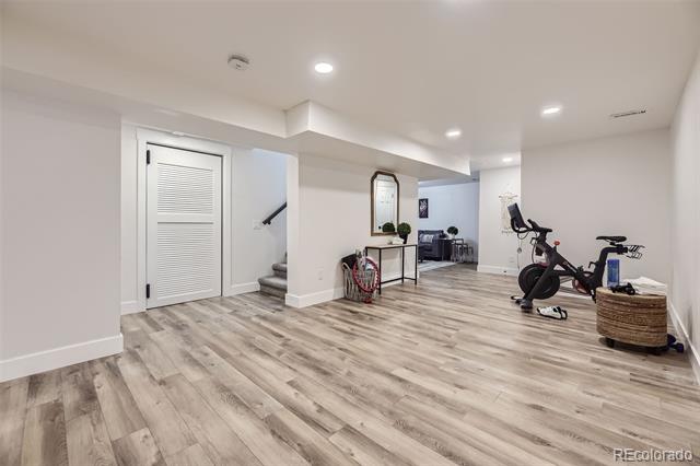 Finished basement recreation room with exercise bikes, gray flooring, and a small sitting area.
