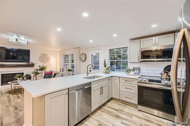 Kitchen with a large white island, stainless steel appliances, and an open living area.