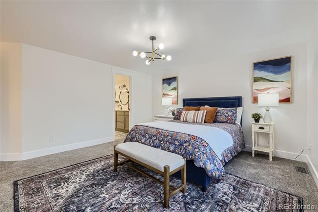 Furnished bedroom with a blue bed, floral bedding, and a bench on a patterned rug.
