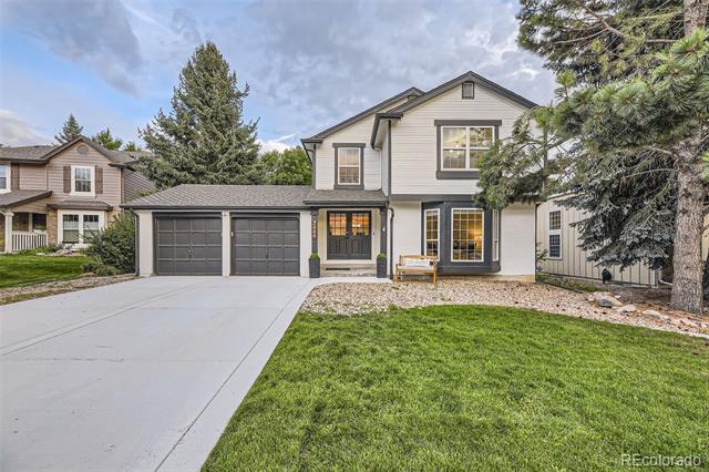 Two-story gray home with a two-car garage, broad driveway, and green front lawn.
