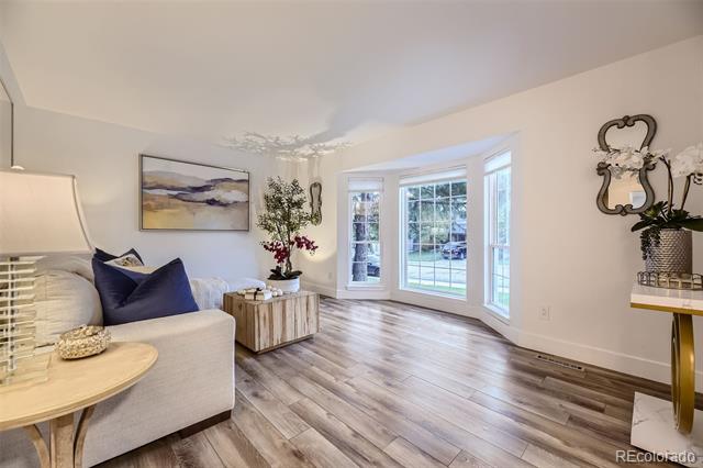 Living room with a bay window overlooking a green yard and wide-plank flooring.