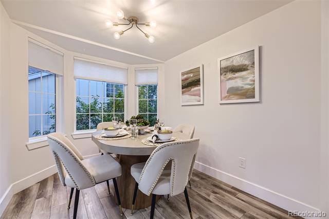 Staged dining room with a set oval table, upholstered chairs, and three windows.